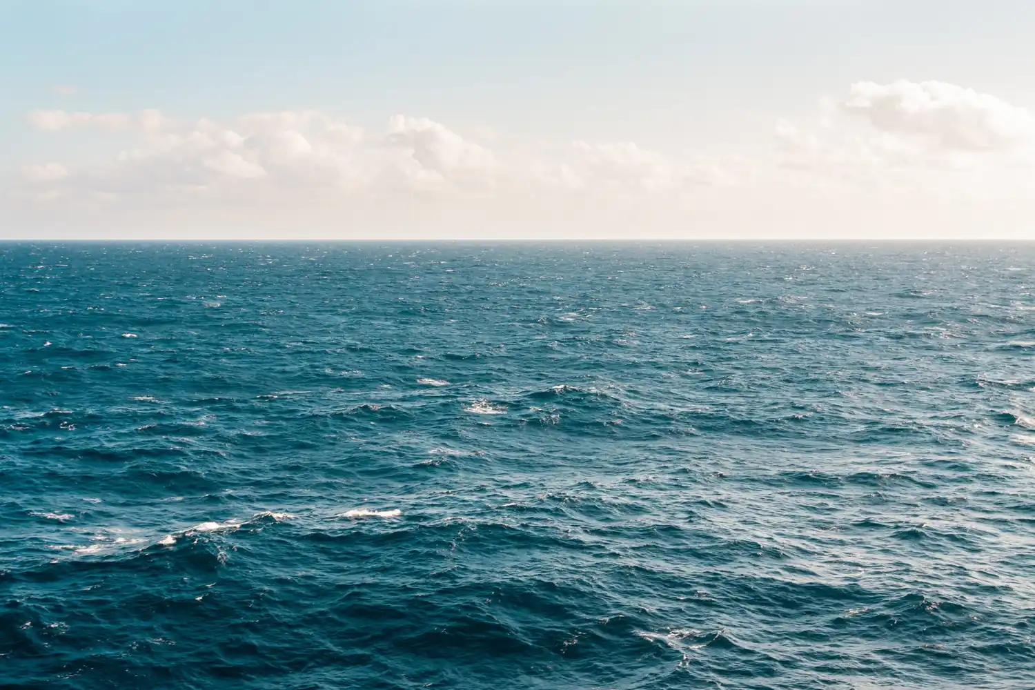 Mare aperto con onde sotto un cielo leggermente nuvoloso.