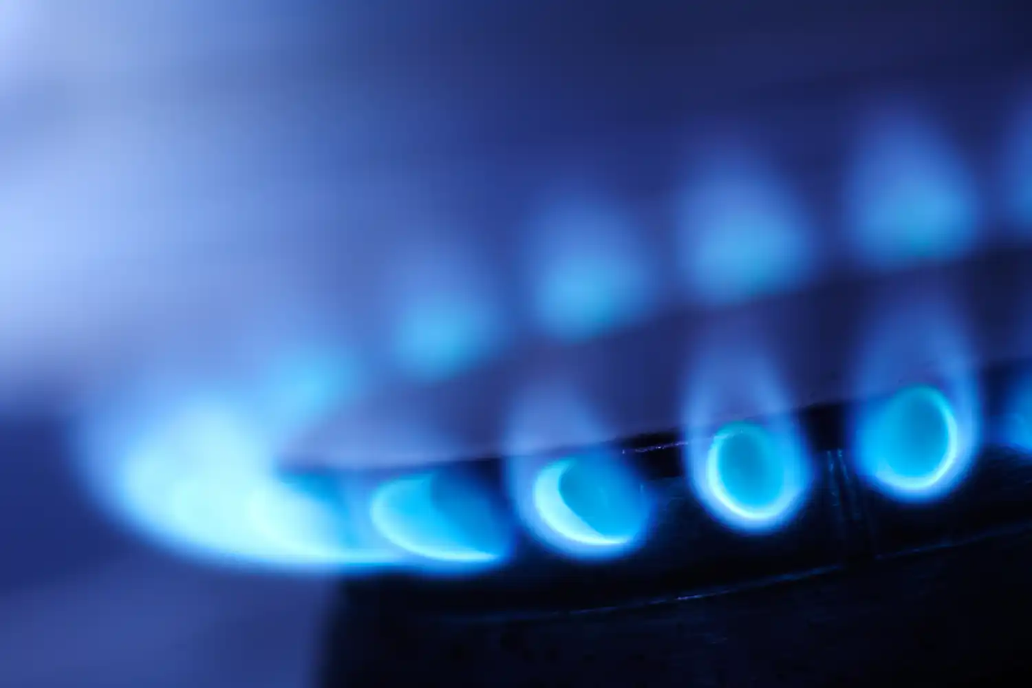 Fiamma blu di un fornello a gas acceso in cucina, vista ravvicinata.