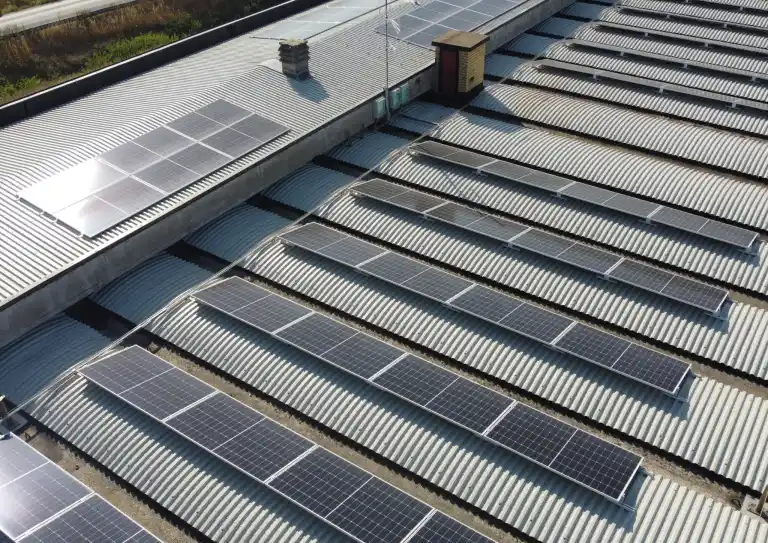 Pannelli solari installati su tetto ondulato di edificio industriale, vista dall'alto.