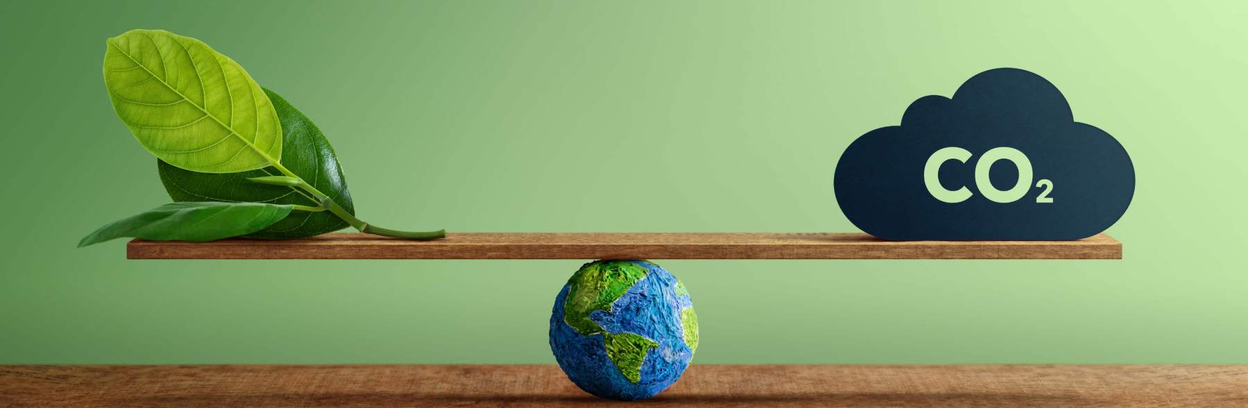 Foglie e simbolo CO2 su una bilancia sopra un globo terrestre, sfondo verde.