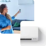 Donna in salotto con telecomando e condizionatore a parete bianco.