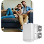 Coppia seduta su divano nero sorride, accanto a un sistema climatizzatore bianco a due ventole.