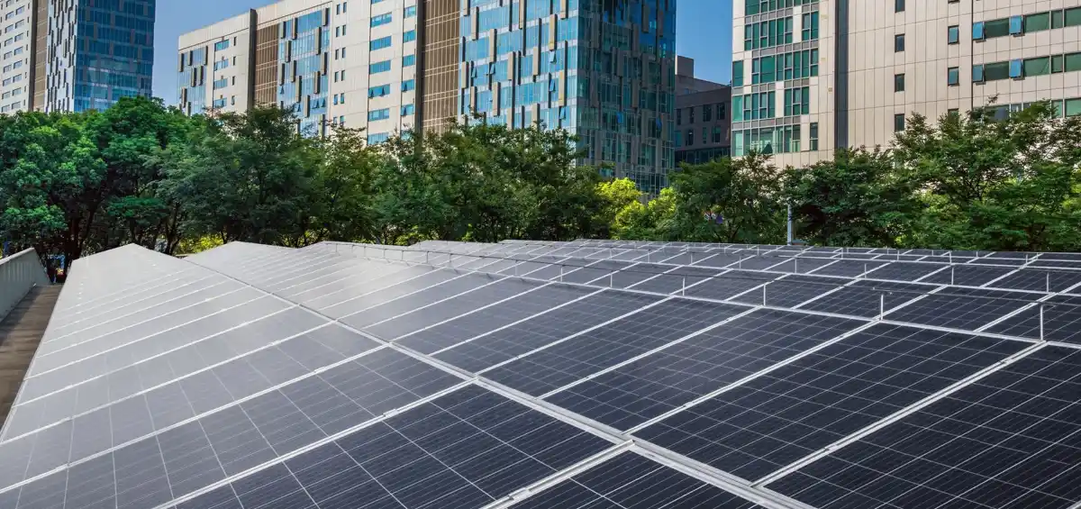 Pannelli solari con edifici moderni sullo sfondo, integrando tecnologia sostenibile in contesto urbano.
