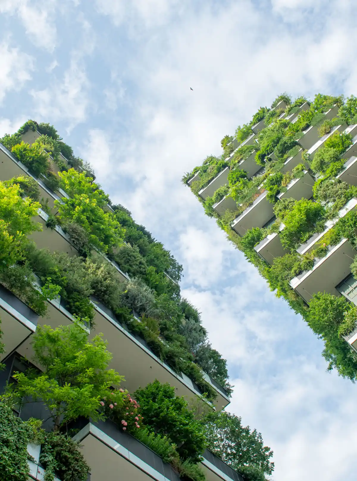 Grattacieli verdi con giardini verticali sotto un cielo azzurro parzialmente nuvoloso.