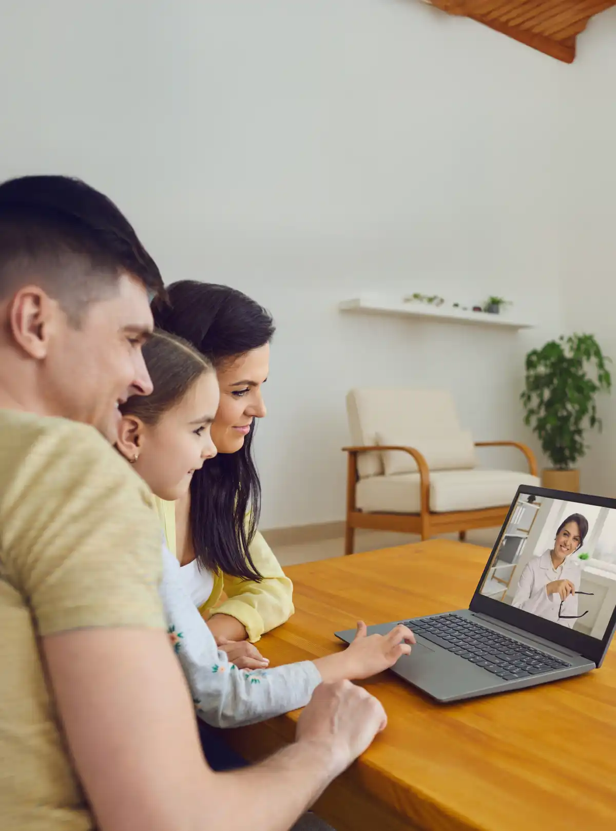 Famiglia in videochiamata col medico su laptop in soggiorno.