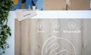 Rappresentazione grafica di Luce, Gas, Rinnovabili su pannello di legno con busta Unoenergy su ripiano.