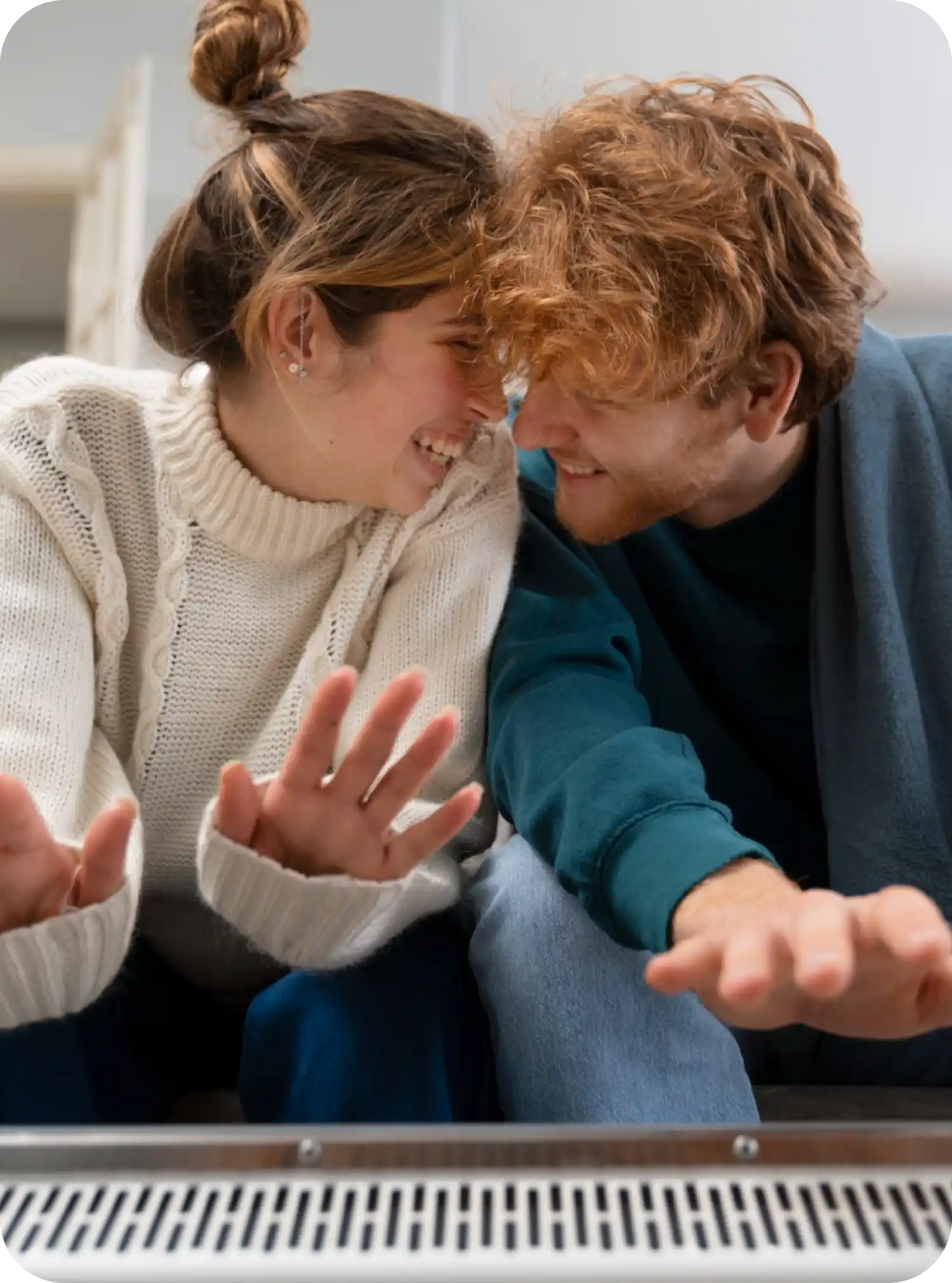 Giovani sorridenti seduti vicini, teste vicine, mani alzate davanti a loro, atmosfera amichevole.