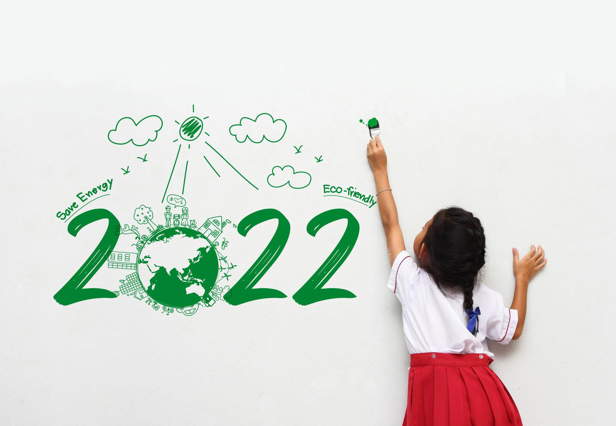 Bambina dipinge su muro con scritta 2022, mondo circondato da disegni eco-friendly, sole e nuvole.