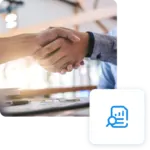 Due persone si stringono la mano sopra una scrivania con documenti e penne. Icona analisi dati visibile.