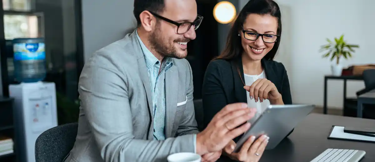 Due colleghi discutono guardando un tablet in un ufficio moderno.