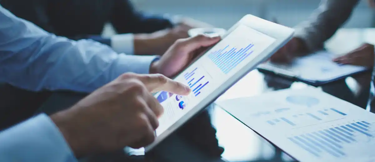 Persona analizza dati su tablet con grafici e report, ambiente ufficio.