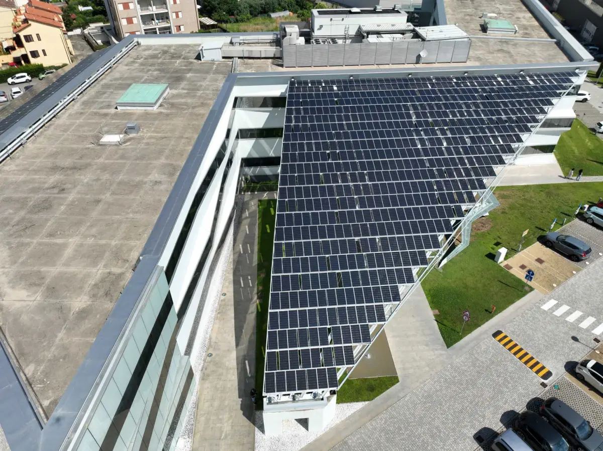 Tetto con pannelli solari su edificio moderno, vista dall'alto, contesto urbano visibile.
