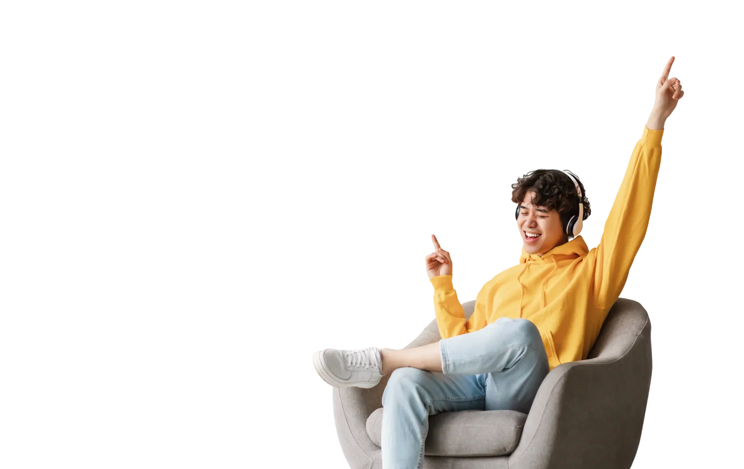 Giovane con cuffie sorride e alza il braccio, seduto su una poltrona grigia, indossa felpa gialla e jeans.