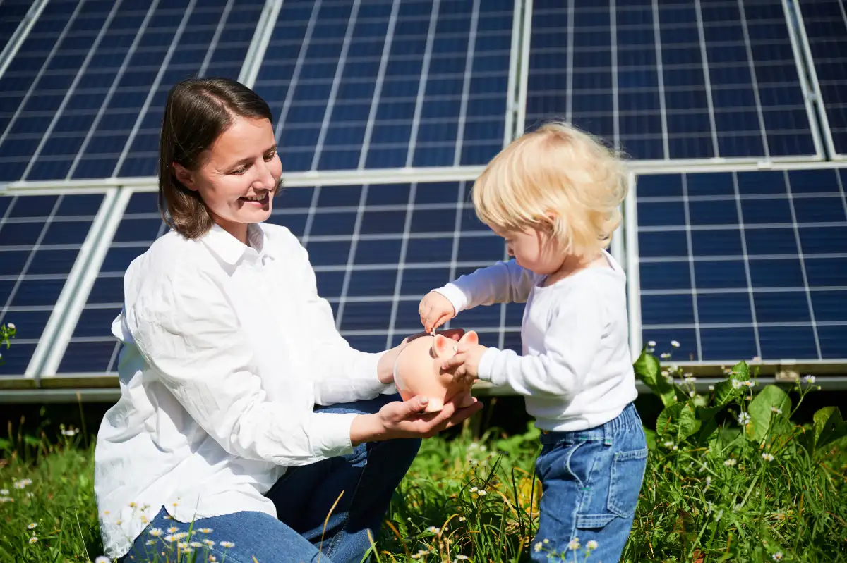 Madre e figlia riempiono salvadanaio davanti a pannelli fotovoltaici