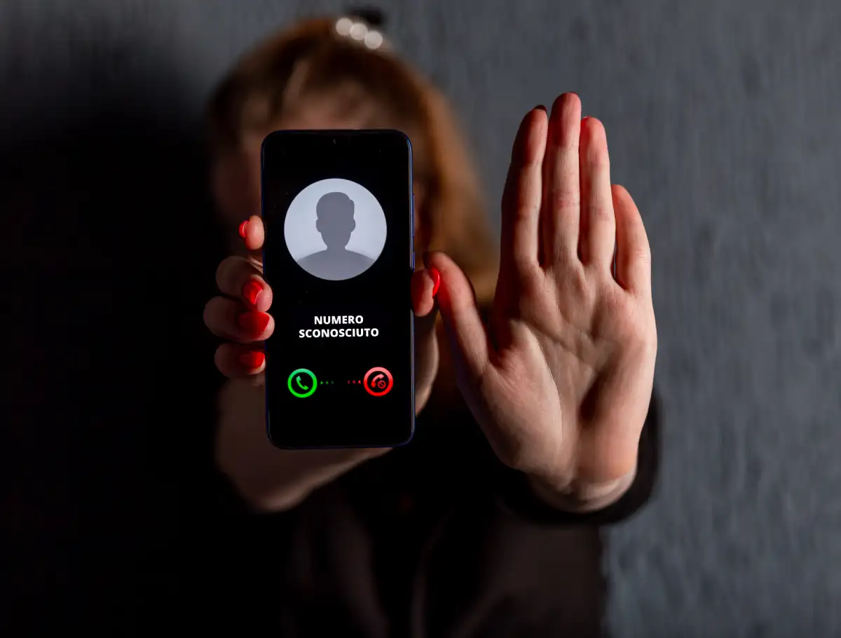 Donna riceve chiamata da numero sconosciuto, con un gesto della mano indica stop