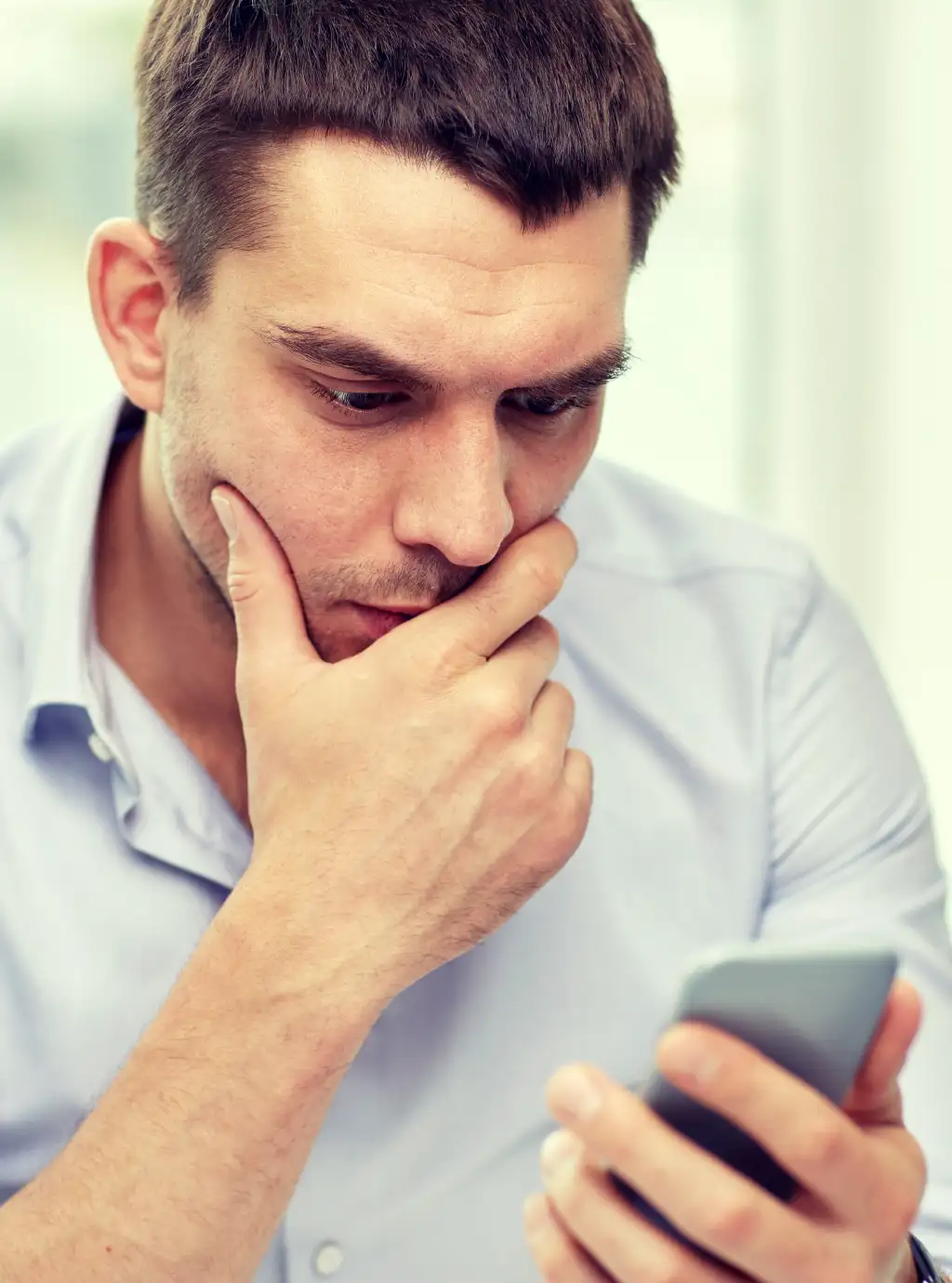 Uomo guarda preoccupato lo schermo dello smartphone