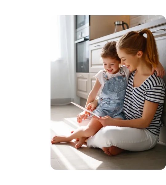 Madre e figlia sedute per terra guardano un tablet