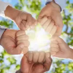 Pugni che si uniscono in cerchio a formare una casa in segno di comunità