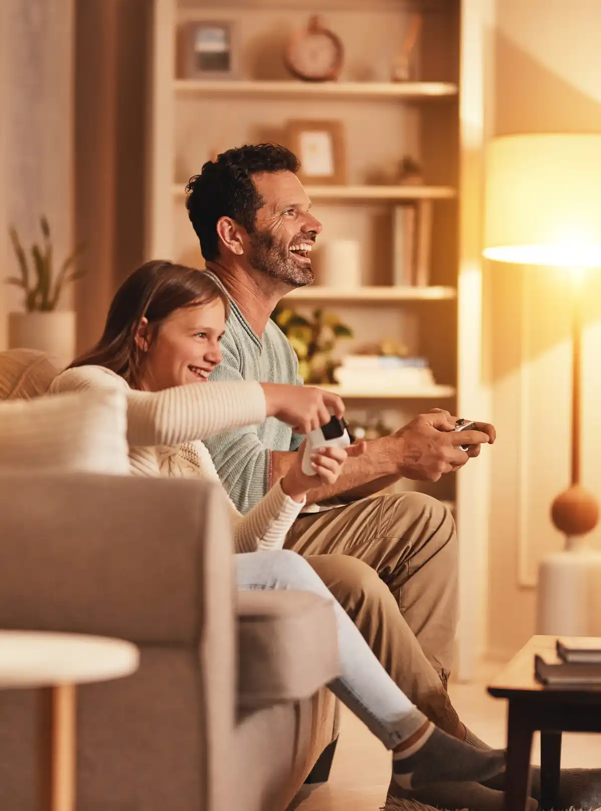 Padre e figlia giocano ai videogiochi in una casa illuminata