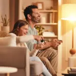 Padre e figlia giocano ai videogiochi in una casa illuminata